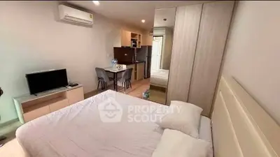Modern studio apartment with cozy bedroom and open kitchen layout, featuring air conditioning and sleek furnishings.