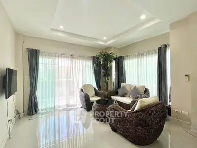 Spacious living room with modern wicker furniture and large windows for natural light.