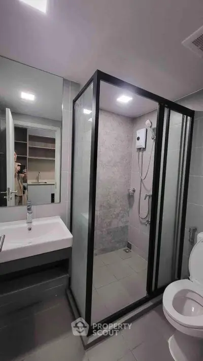 Modern bathroom with glass shower enclosure and sleek fixtures in a contemporary apartment.