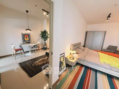 Stylish modern bedroom with colorful rug and adjacent dining area in open layout apartment.