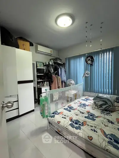 Cozy bedroom with modern decor and ample storage space, featuring a playful bedspread and natural light.