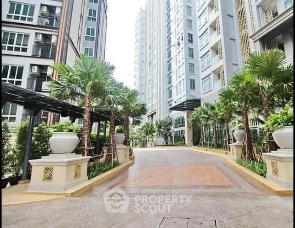 Luxurious modern apartment building entrance with lush greenery and palm trees.