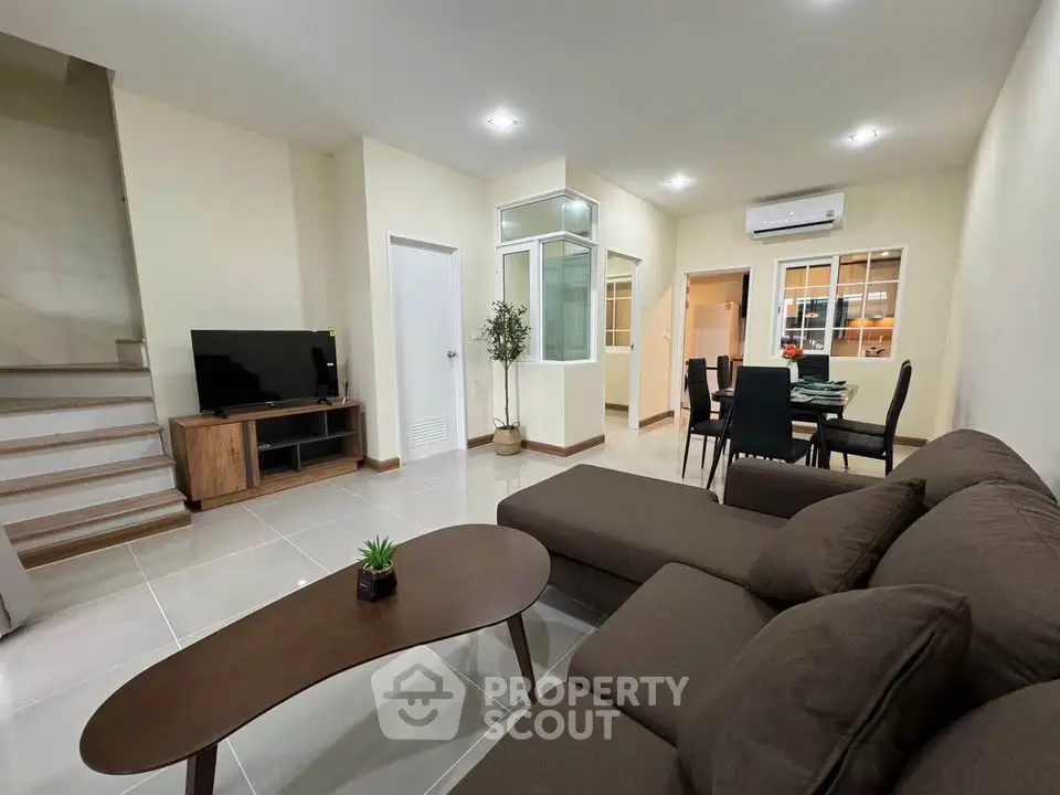 Spacious modern living room with cozy brown sofa and dining area, perfect for family gatherings.