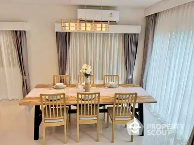 Elegant dining room with wooden table and chairs, surrounded by sheer curtains and modern lighting.