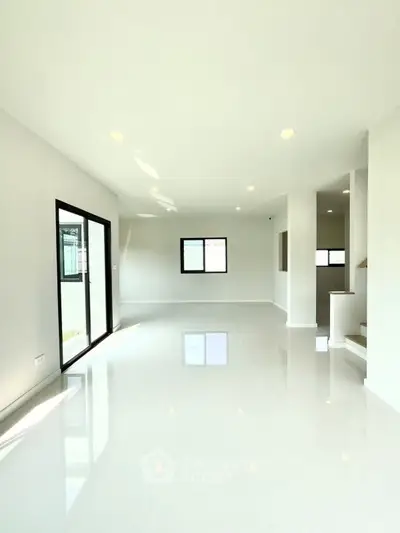 Spacious modern living room with large windows and bright white flooring