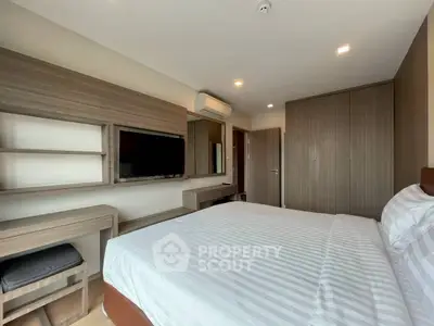 Modern bedroom with built-in wardrobe and wall-mounted TV in stylish apartment.