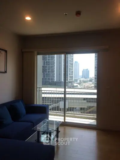 Modern living room with city view from balcony, featuring sleek furniture and natural light.