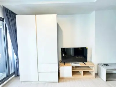 Modern living room with sleek white wardrobe and flat-screen TV on wooden stand.