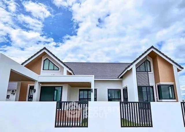 Modern single-story house with stylish roof and large windows under a blue sky.