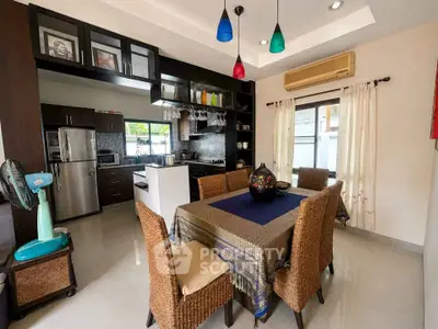 Charming dining area with wicker chairs and modern kitchen featuring stainless steel appliances and colorful pendant lights.