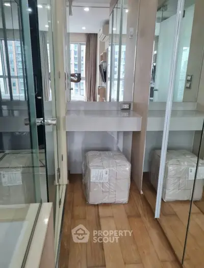 Modern compact bedroom with mirrored closet and city view, featuring sleek wooden flooring and contemporary design.