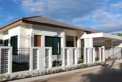 Modern single-story house with stylish fence and landscaped garden under a clear blue sky.