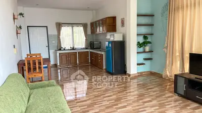 Spacious living room with open kitchen, wooden flooring, and modern appliances.