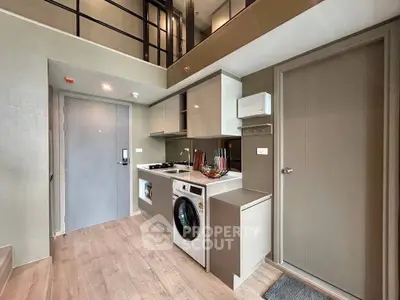Modern compact kitchen with washing machine and sleek cabinetry in a stylish apartment.