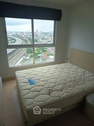 Cozy bedroom with large window offering stunning city view, featuring a comfortable bed and wooden flooring.