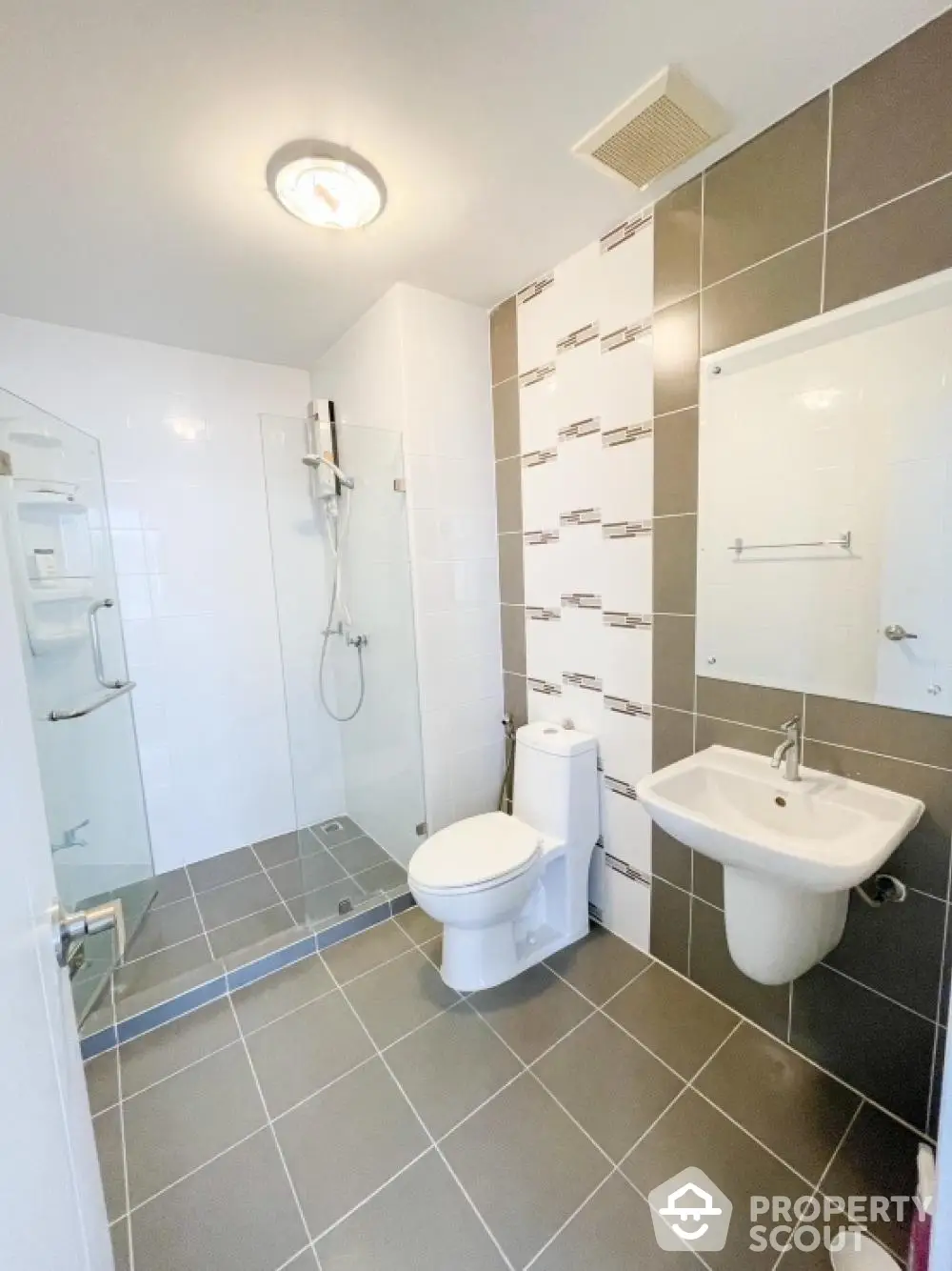 Pristine modern bathroom with walk-in shower, sleek tiling, and essential fixtures, perfect for a refreshing start to the day.