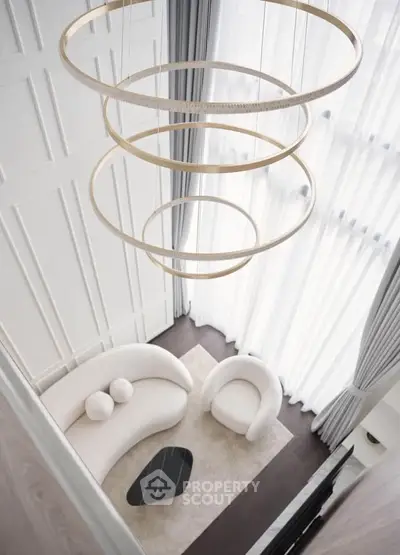 Luxurious modern living room with elegant chandelier and stylish furniture, featuring a cozy sofa and armchair.