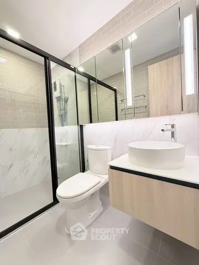 Modern bathroom with sleek design, featuring glass shower and elegant fixtures.