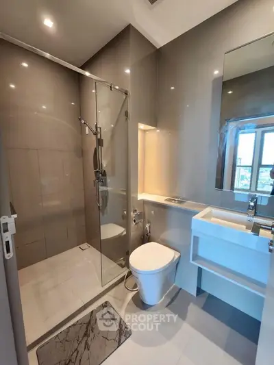 Modern bathroom with glass shower and sleek fixtures in contemporary apartment.