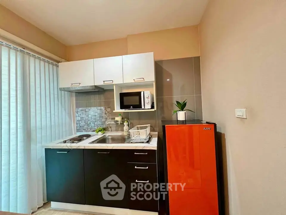 Modern compact kitchen with red fridge and sleek cabinetry