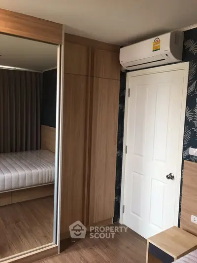Modern bedroom with wooden wardrobe and air conditioning unit, featuring a cozy bed and stylish decor.
