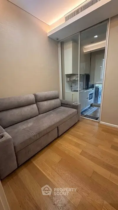 Cozy living room with modern sofa and sliding glass doors leading to a compact kitchen.