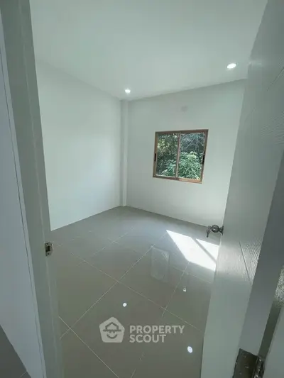 Bright empty room with tiled floor and window view of greenery, ideal for customization.