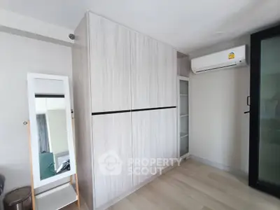 Modern bedroom with sleek wardrobe and air conditioning unit, perfect for comfortable living.