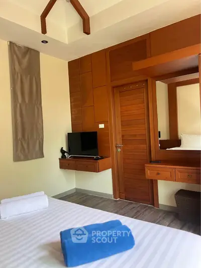 Cozy bedroom with modern wooden accents and a mounted TV, perfect for relaxation.