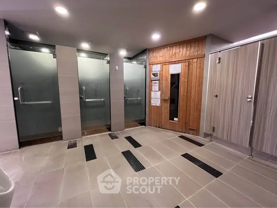 Modern communal sauna and shower area with sleek design and wooden accents.