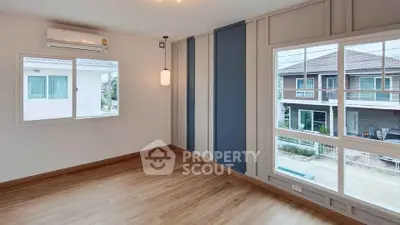 Spacious empty room with large windows and wooden flooring in modern home