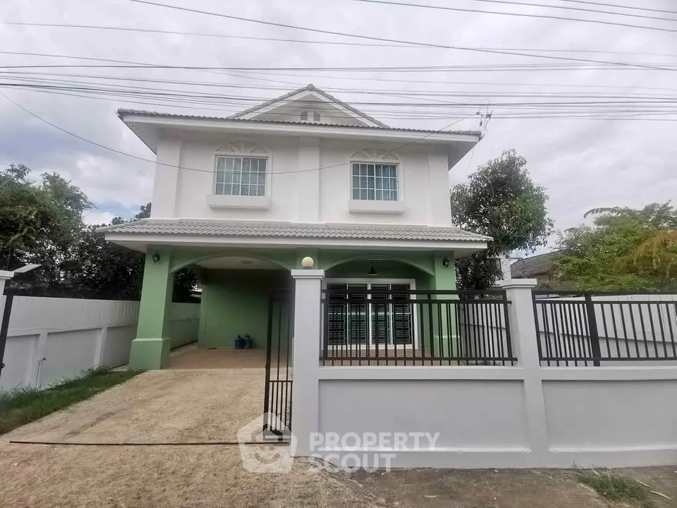 Charming two-story house with gated driveway and lush greenery, perfect for family living.