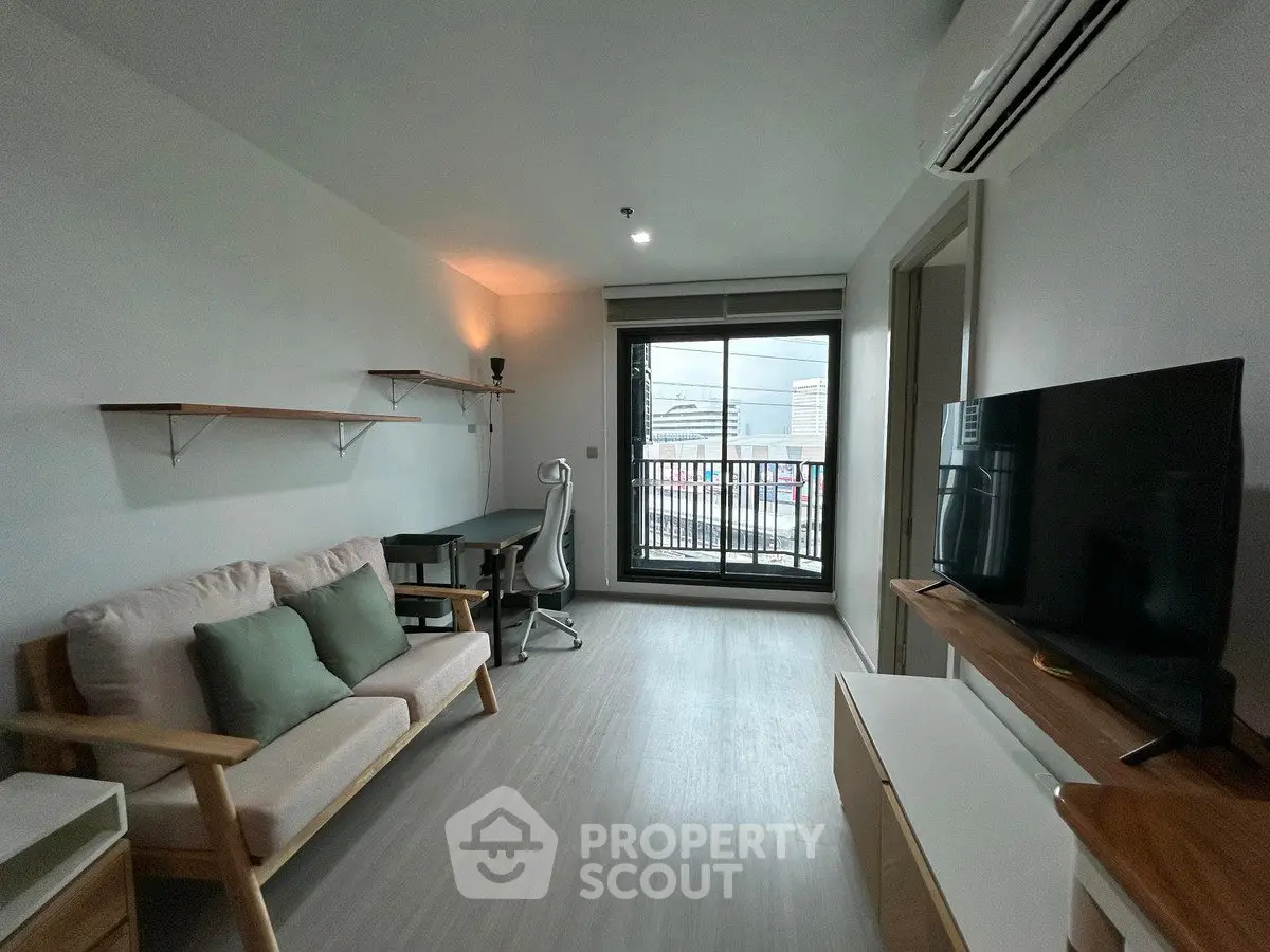 Modern living room with balcony view, featuring sleek furniture and natural light.
