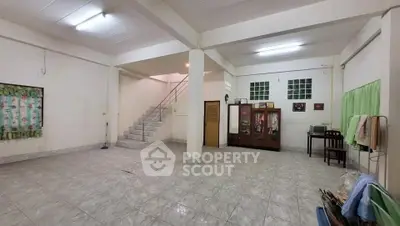 Spacious open-plan living area with tiled flooring and staircase, ideal for customization.