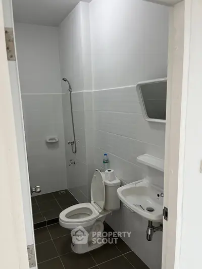 Modern bathroom with sleek white tiles and essential fixtures, perfect for a minimalist home design.