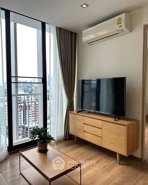 Modern living room with city view, featuring sleek furniture and large windows.