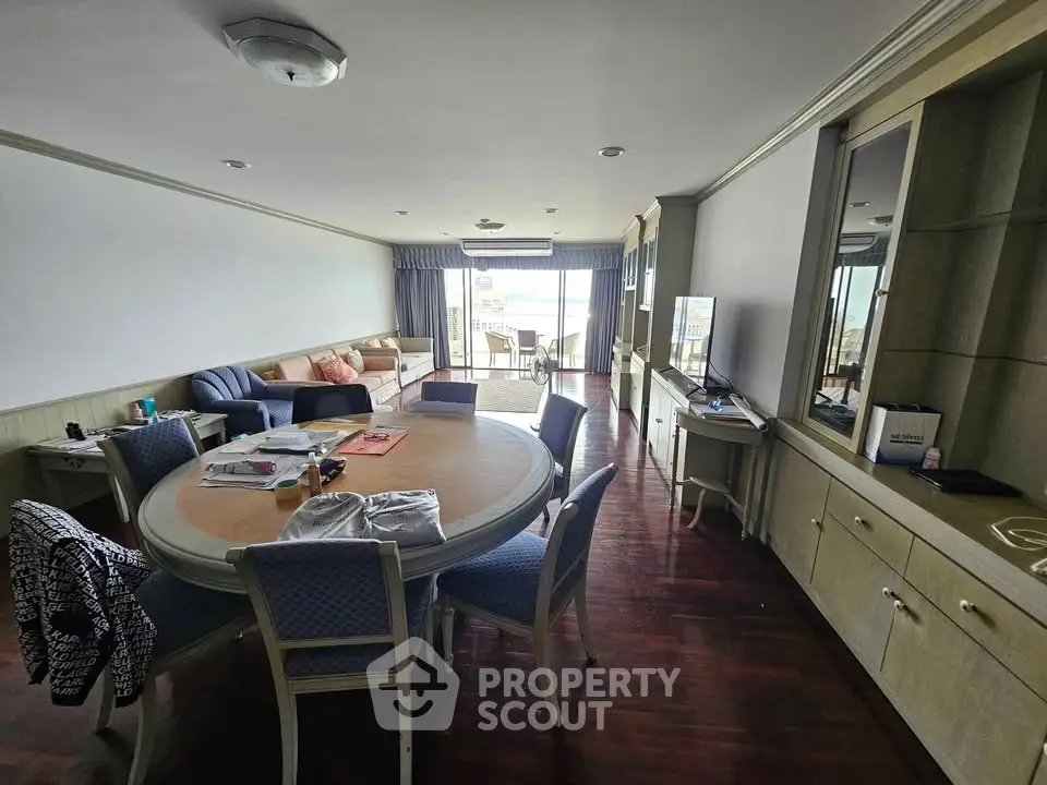 Spacious living room with elegant dining area and large windows offering natural light.