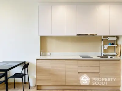 Sleek modern kitchen with minimalist design, featuring light wood cabinetry and a compact dining area, perfect for urban living.