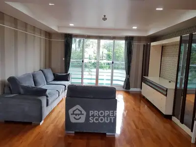 Spacious living room with modern furniture and large windows overlooking greenery.