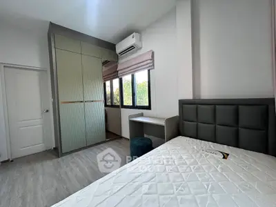 Modern bedroom with large windows and built-in wardrobe, featuring sleek design and natural light.
