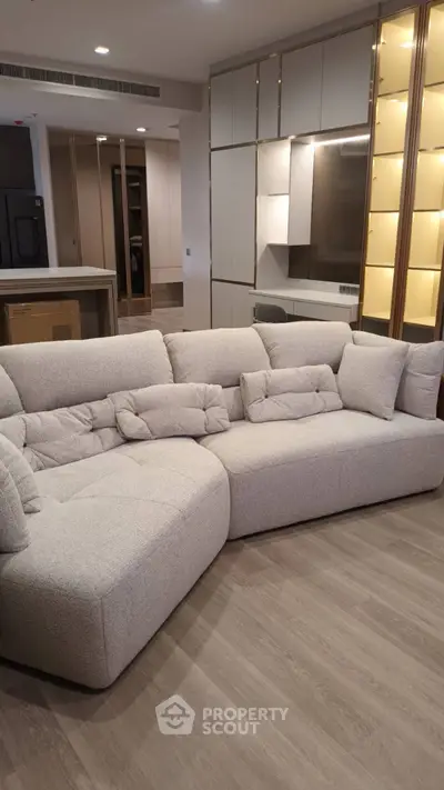 Modern living room with stylish beige sectional sofa and sleek cabinetry
