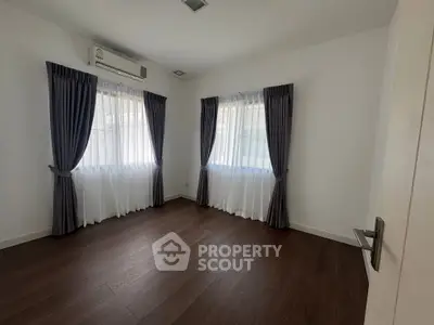 Spacious bedroom with elegant curtains and wooden flooring, perfect for a cozy retreat.
