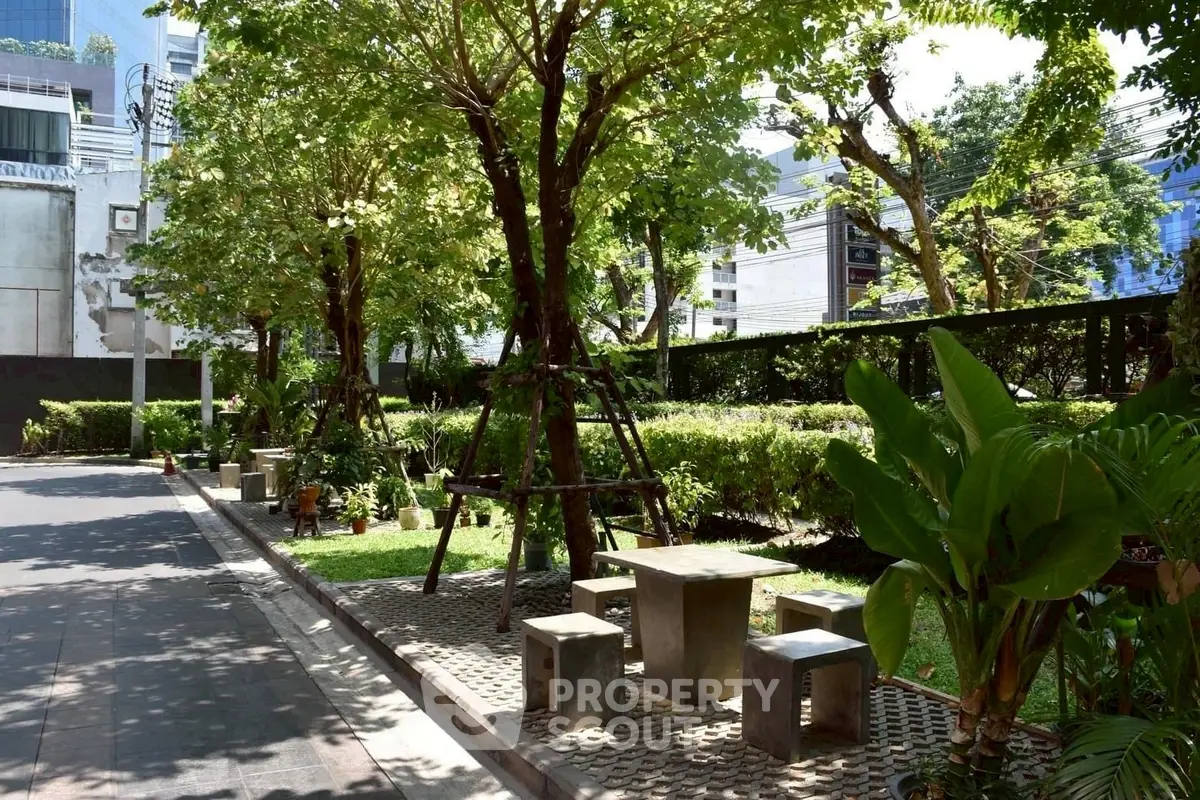 Charming urban garden with seating area, lush greenery, and modern city backdrop.