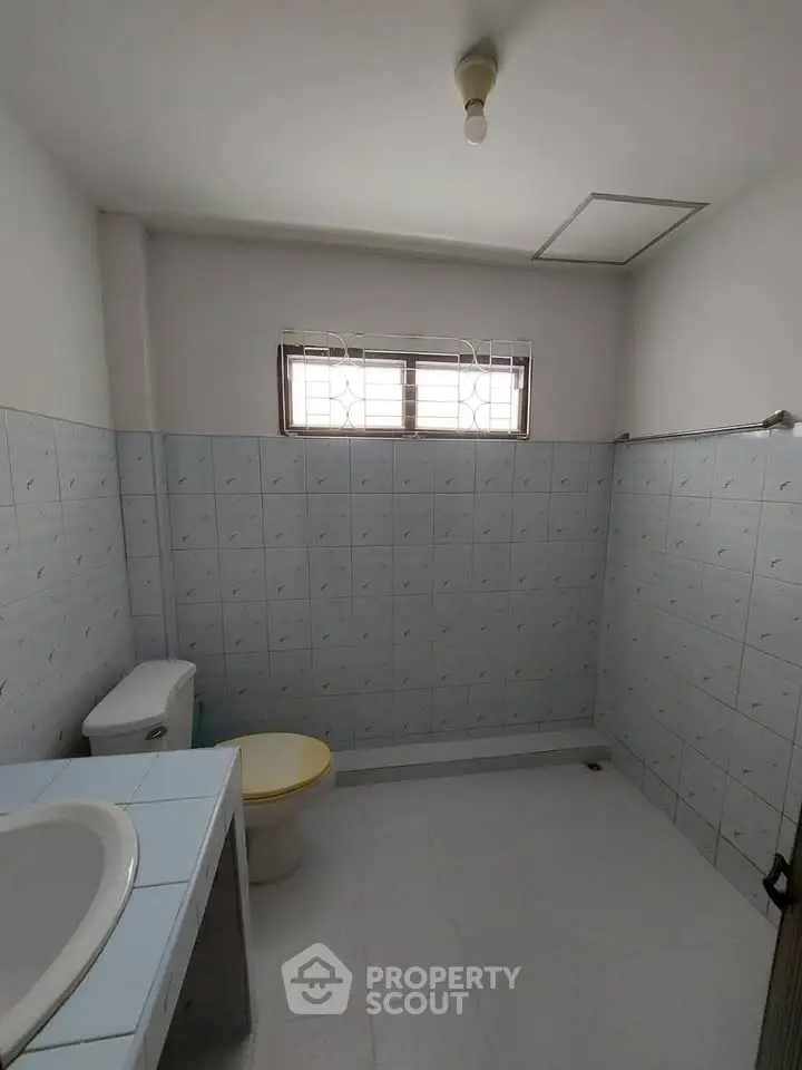 Spacious bathroom with tiled walls and natural light from window