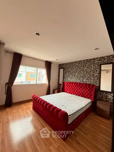 Spacious bedroom with elegant red velvet bed and stylish wallpaper, perfect for modern living.