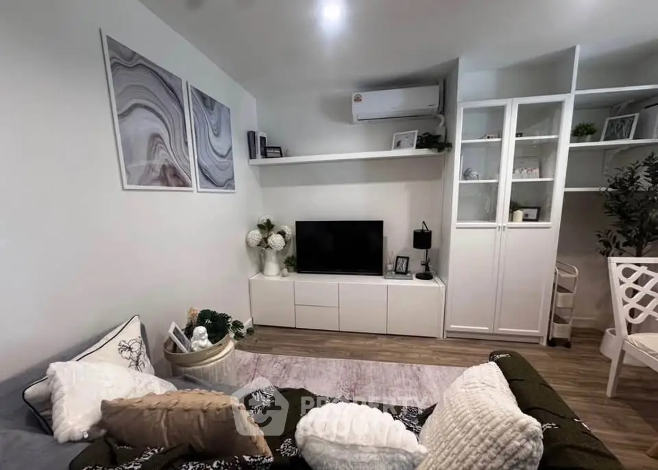 Cozy living room with modern decor, featuring a TV unit, stylish shelving, and comfortable seating.