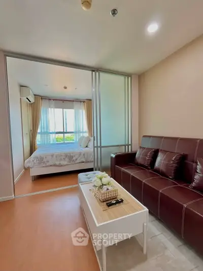 Modern living room with sliding glass doors leading to a cozy bedroom, featuring stylish furniture and natural light.