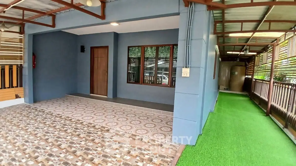 Charming covered patio with tiled flooring and artificial grass, perfect for outdoor relaxation.