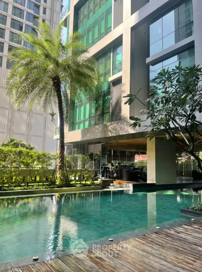Luxurious modern building with serene pool and lush greenery in urban setting.