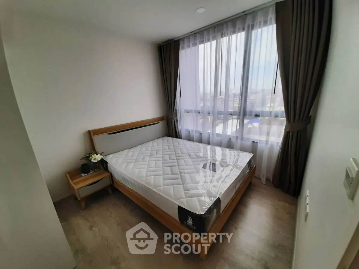 Cozy bedroom with large window and modern furnishings, perfect for relaxation and comfort.